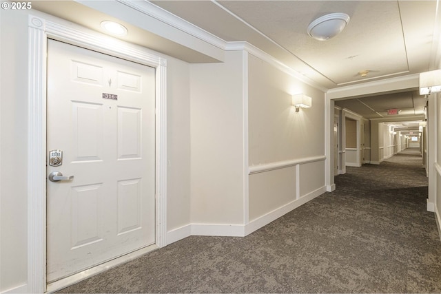 hallway featuring dark colored carpet and ornamental molding