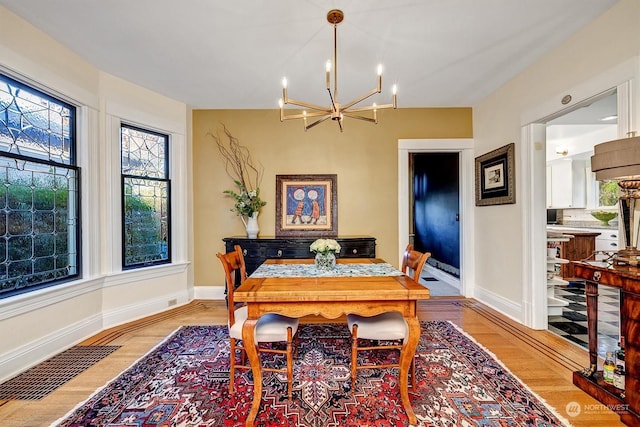 dining area with light hardwood / wood-style floors and a chandelier