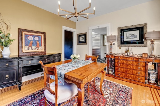 dining space with light hardwood / wood-style floors and a chandelier