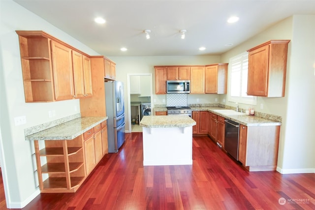 kitchen with sink, light stone counters, a center island, dark hardwood / wood-style floors, and stainless steel appliances