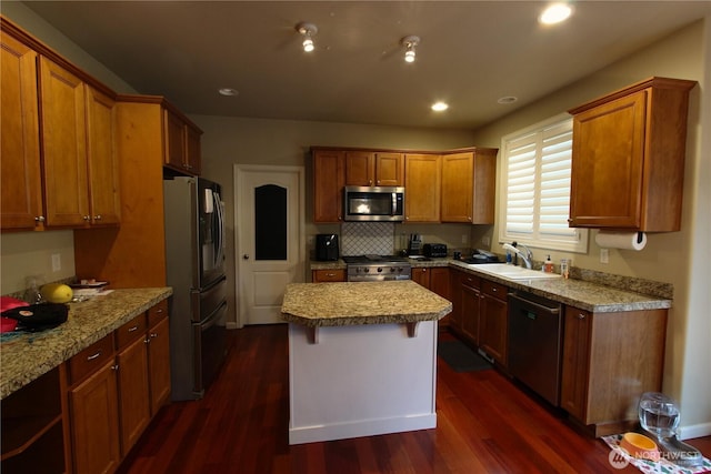 kitchen featuring appliances with stainless steel finishes, dark wood-style flooring, a sink, and a center island