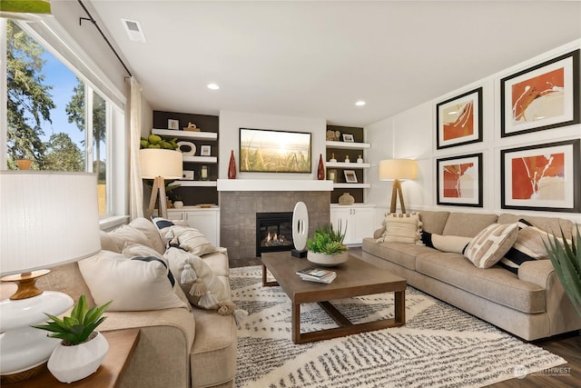 living room featuring built in shelves, a fireplace, and hardwood / wood-style floors