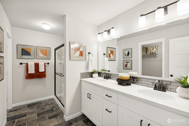 bathroom featuring tasteful backsplash, vanity, and a shower with door