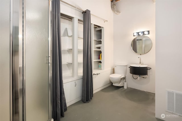 bathroom with toilet, concrete floors, and sink