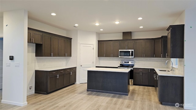 kitchen with sink, dark brown cabinets, stainless steel appliances, a center island, and light wood-type flooring