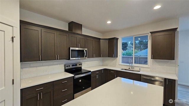 kitchen with dark brown cabinetry, stainless steel appliances, a sink, light countertops, and backsplash