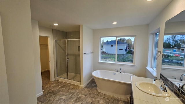 full bathroom with a freestanding tub, vanity, baseboards, a shower stall, and a walk in closet