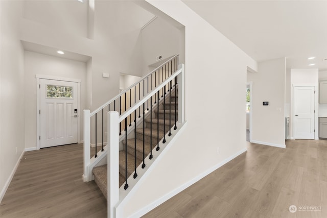 staircase with hardwood / wood-style flooring and a towering ceiling