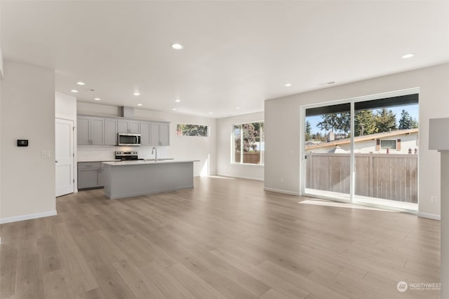 unfurnished living room with sink and light wood-type flooring