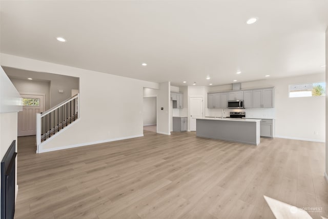 unfurnished living room with sink and light hardwood / wood-style flooring