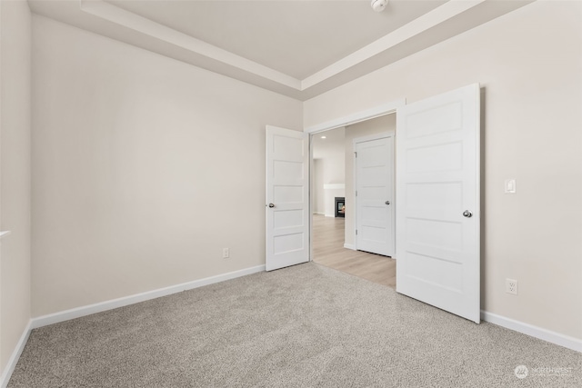 unfurnished bedroom with a tray ceiling and light carpet