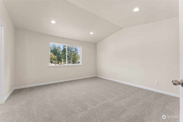 carpeted empty room featuring lofted ceiling