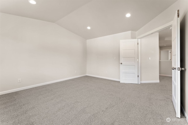 carpeted empty room with lofted ceiling