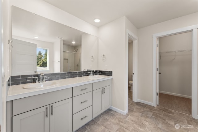 bathroom with vanity, toilet, an enclosed shower, and decorative backsplash