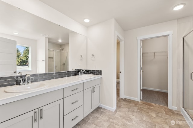 bathroom featuring tasteful backsplash, vanity, toilet, and walk in shower