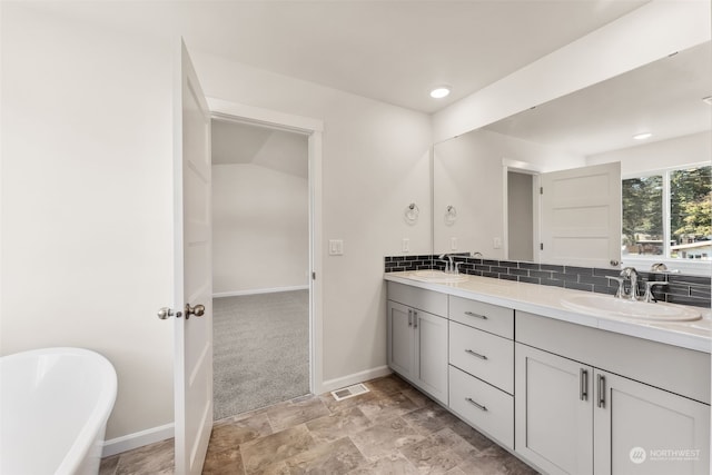 bathroom with a tub to relax in, vanity, and backsplash