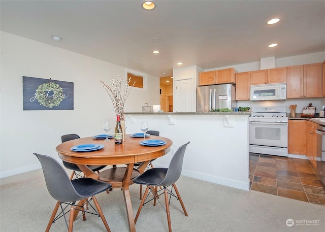 kitchen with a kitchen bar, white appliances, and stone countertops