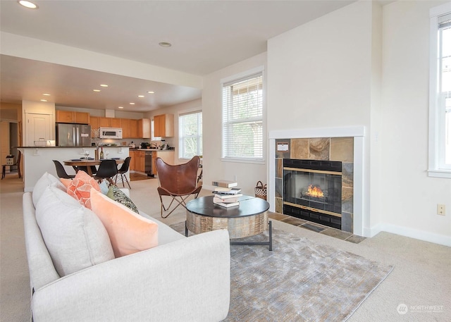 living room featuring light colored carpet and a tiled fireplace