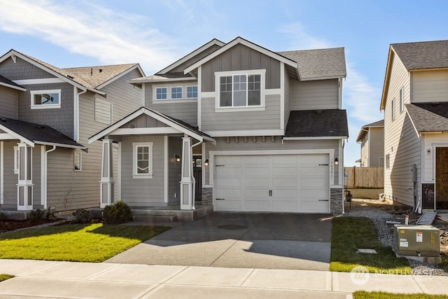 view of front of home featuring board and batten siding, fence, concrete driveway, a garage, and stone siding