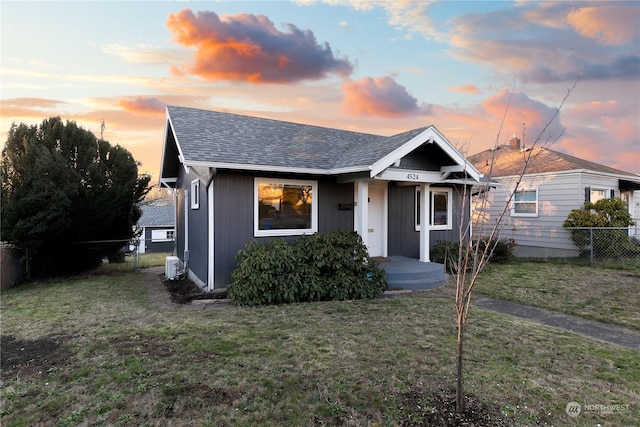 bungalow with central AC unit and a lawn