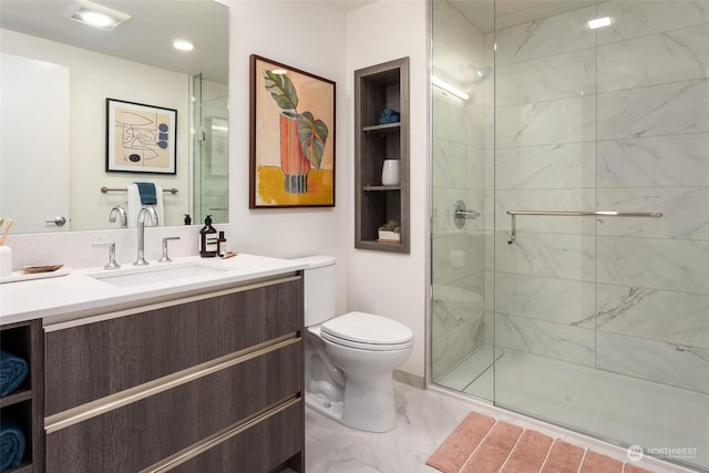 bathroom featuring toilet, vanity, and a shower with door