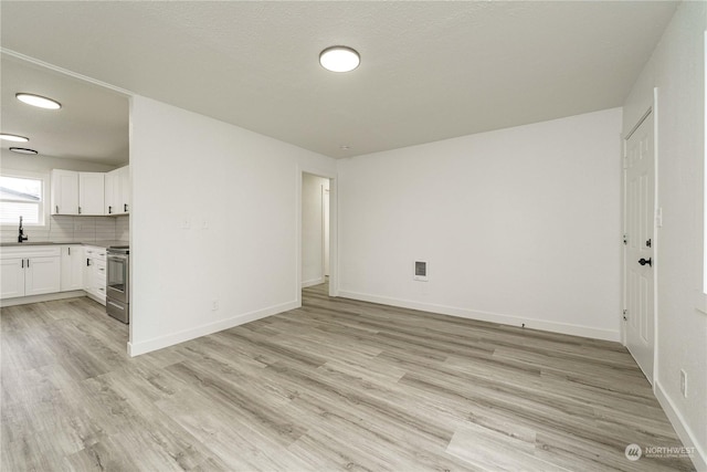 unfurnished living room with light hardwood / wood-style floors and sink