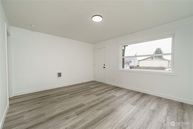 unfurnished room featuring a textured ceiling and light hardwood / wood-style flooring