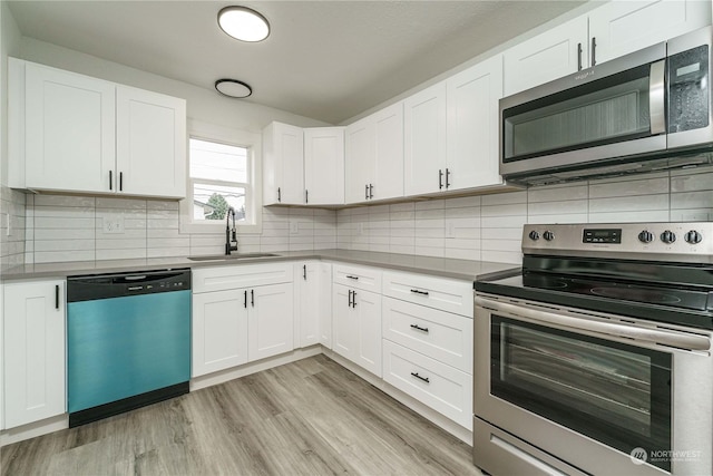 kitchen with backsplash, sink, white cabinetry, light wood-type flooring, and stainless steel appliances