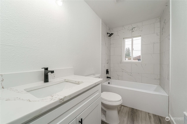 full bathroom featuring toilet, tiled shower / bath, hardwood / wood-style flooring, and vanity