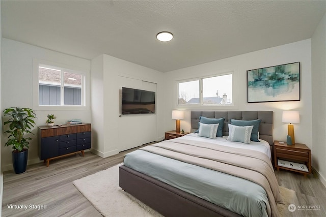 bedroom with a textured ceiling and light hardwood / wood-style flooring