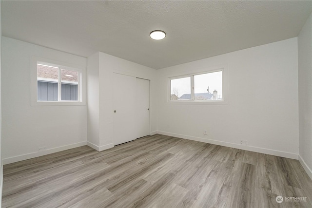 spare room with a textured ceiling and light hardwood / wood-style flooring