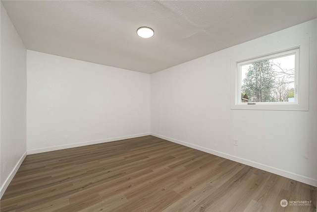 spare room with a textured ceiling and dark hardwood / wood-style flooring