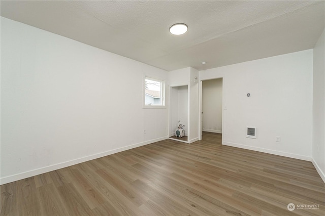 unfurnished room with a textured ceiling and hardwood / wood-style floors