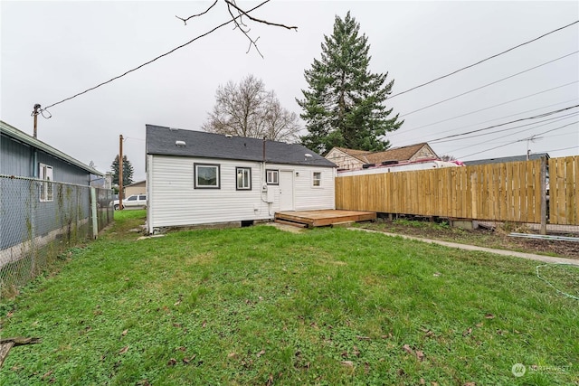 rear view of house with a lawn and a wooden deck