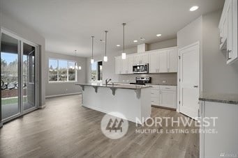 kitchen featuring pendant lighting, appliances with stainless steel finishes, a center island with sink, and white cabinets