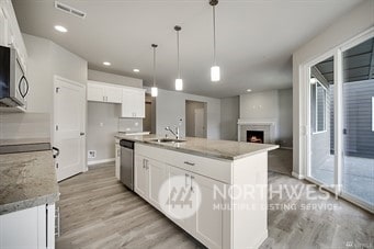 kitchen with pendant lighting, white cabinetry, and a center island with sink