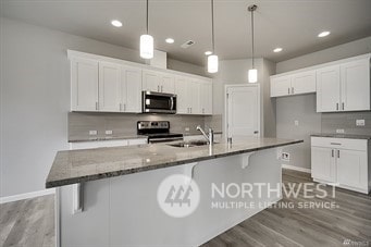 kitchen with hanging light fixtures, white cabinetry, appliances with stainless steel finishes, and dark stone counters