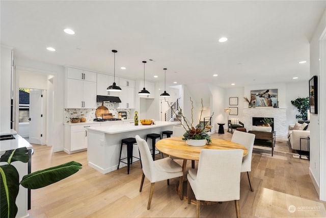 dining room with light wood-type flooring and a stone fireplace