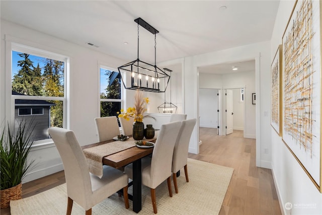 dining room with light wood-type flooring and a notable chandelier