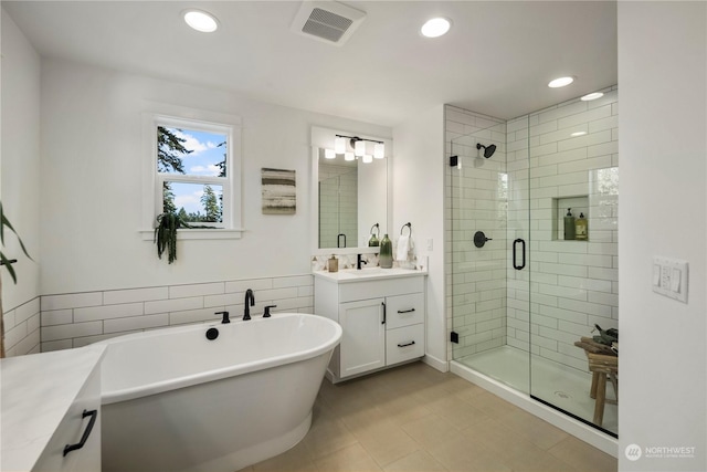 bathroom with tile walls, tile patterned floors, vanity, and independent shower and bath