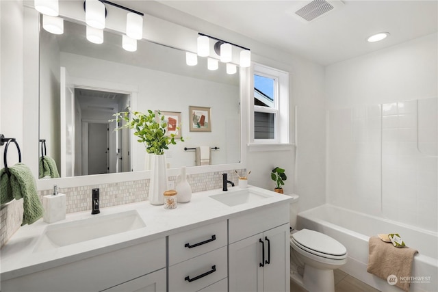 full bathroom featuring toilet, decorative backsplash, washtub / shower combination, and vanity