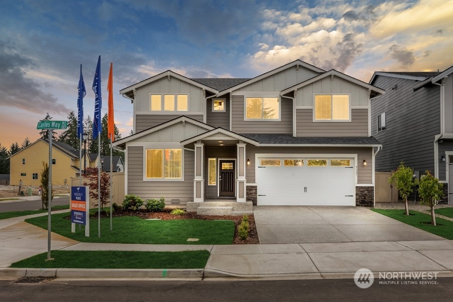 craftsman inspired home with a garage and a yard