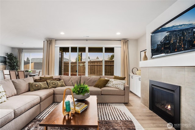 living room featuring light wood-style floors, a tile fireplace, and recessed lighting