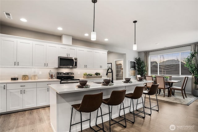 kitchen with light countertops, appliances with stainless steel finishes, light wood-type flooring, and visible vents