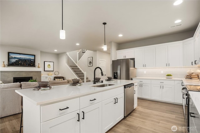 kitchen featuring stainless steel appliances, open floor plan, visible vents, and a sink