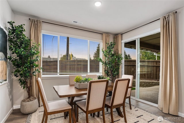 dining area featuring light wood-type flooring, visible vents, and baseboards