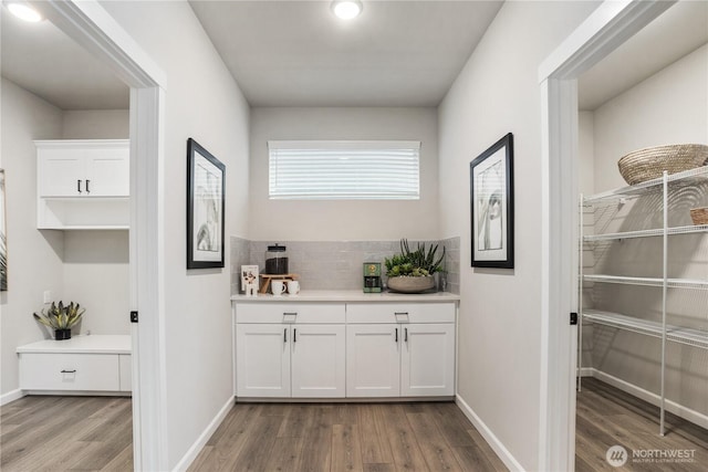 bar featuring baseboards, backsplash, and light wood finished floors