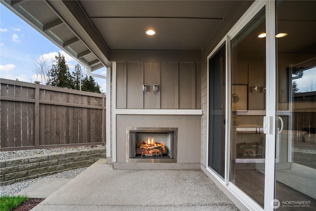 view of patio / terrace with a warm lit fireplace and fence