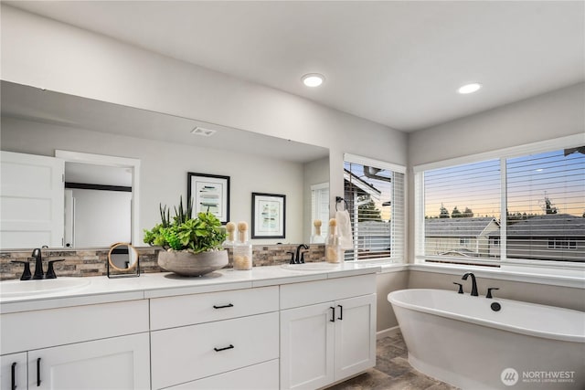 full bath with a freestanding tub, recessed lighting, a sink, visible vents, and double vanity