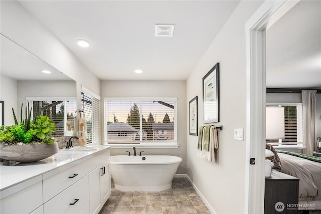 full bathroom featuring visible vents, ensuite bathroom, vanity, a freestanding tub, and baseboards